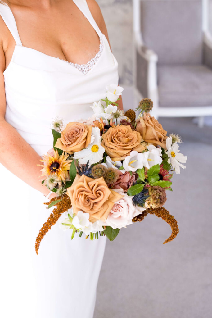 Bride holding autumn wedding flowers including toffee roses at Eastington Park