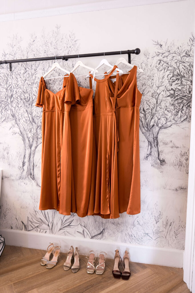 Satin rust coloured bridesmaids dresses hanging in the dressing room at Eastington Park